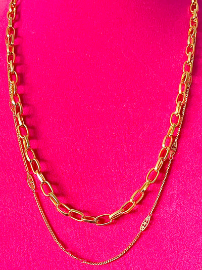 Yellow brass chain necklaces on a pink backdrop