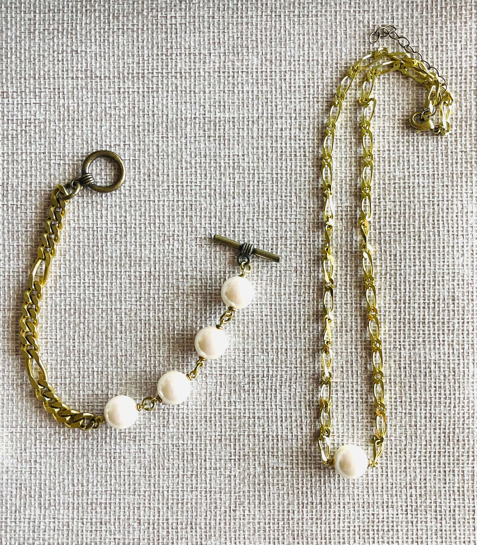 Yellow brass and white pearl necklace adn bracelet on tan background 