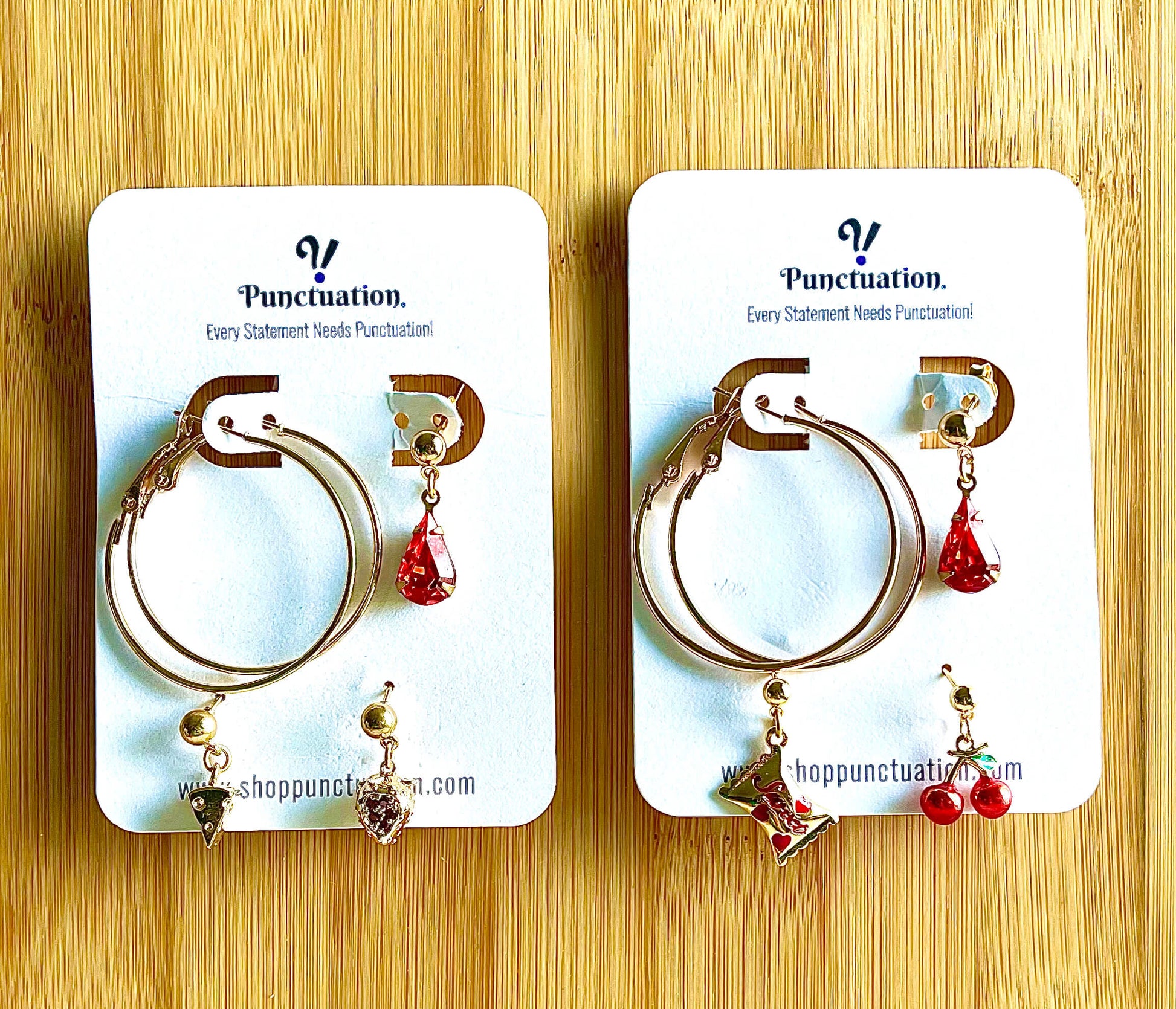Pair of hoop earrings with red and black heart charms on Punctuation branded cards.