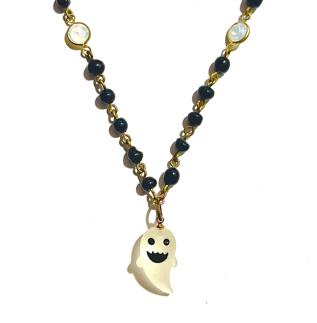 Black bead necklace with white ghost charm on white background. 