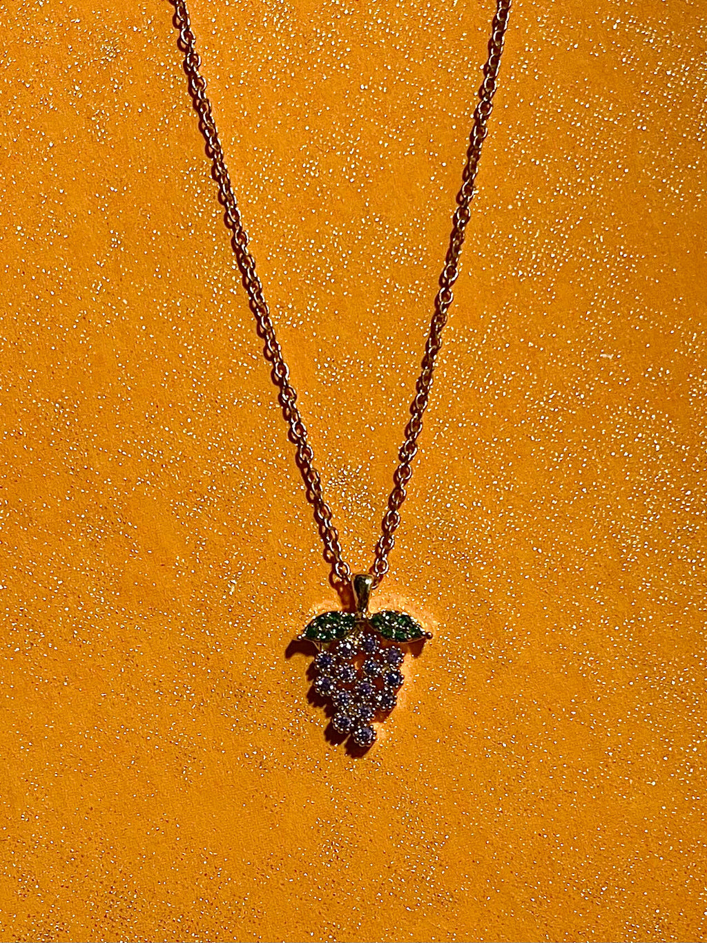 Grape charm necklace on a yellow background
