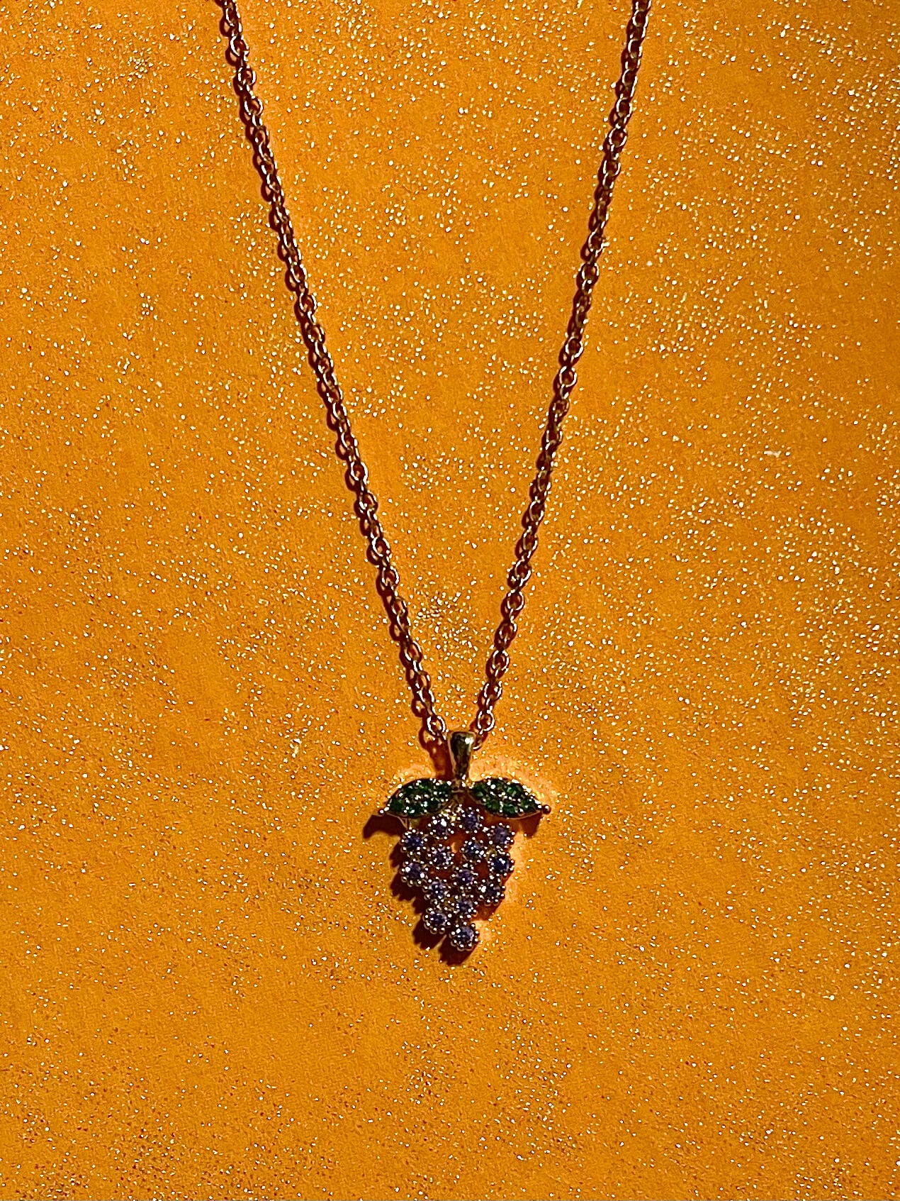 Grape charm necklace on a yellow background