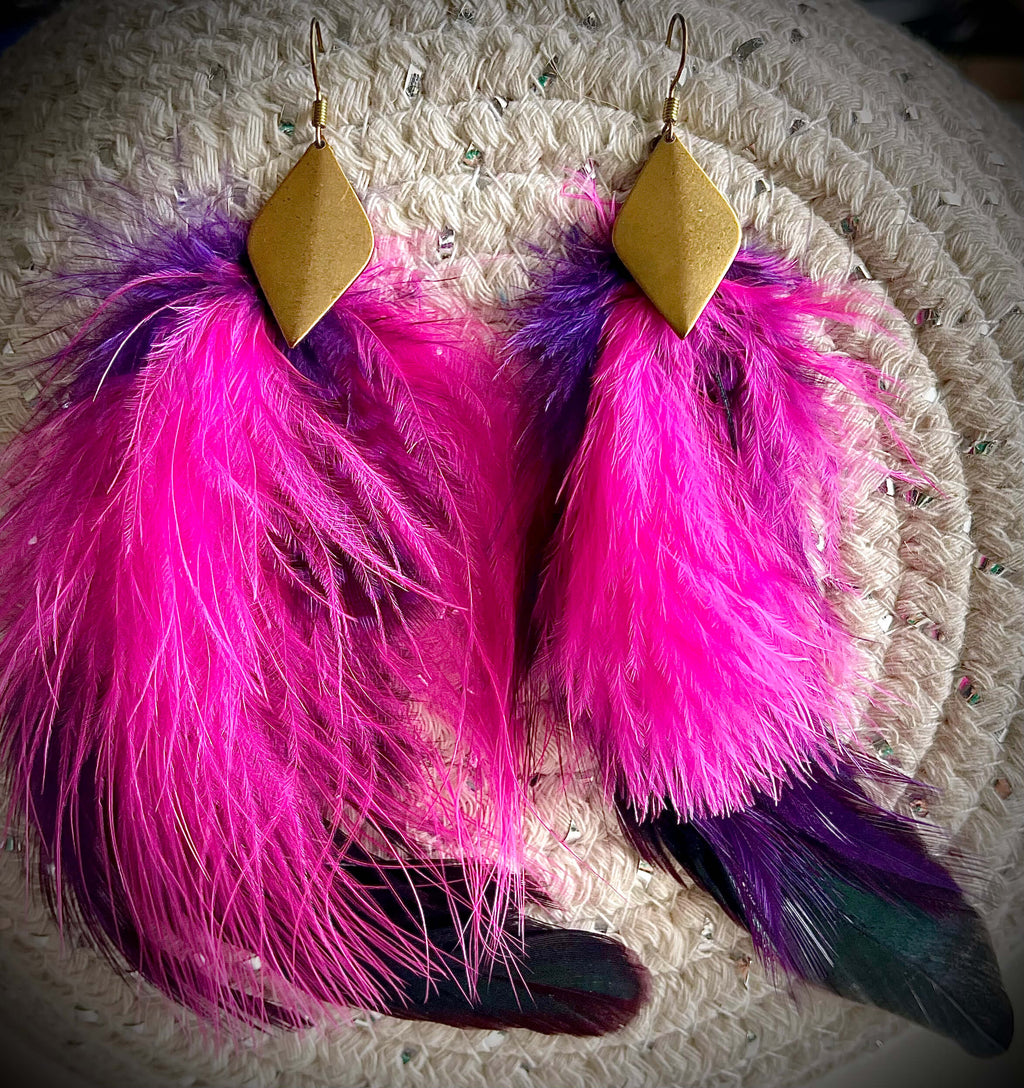 Pink and purple feather earrings with diamond shaped brass pendant on white background