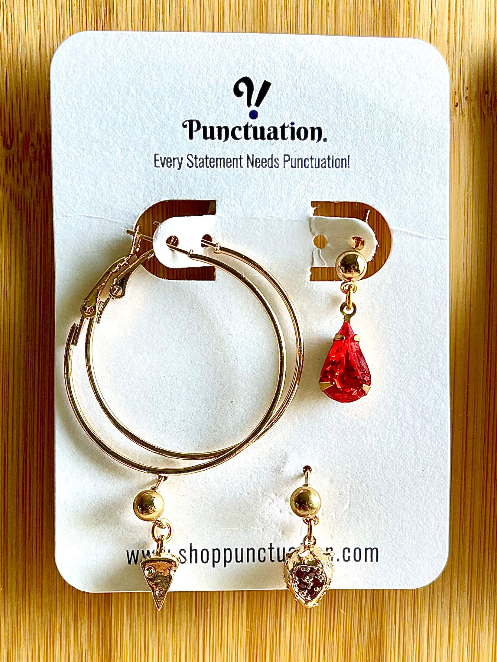 Yellow brass earring set with pair of vintage hoop earrings, red crystal drop earring, cheese wedge charm earring, and red crystal strawberry drop earring