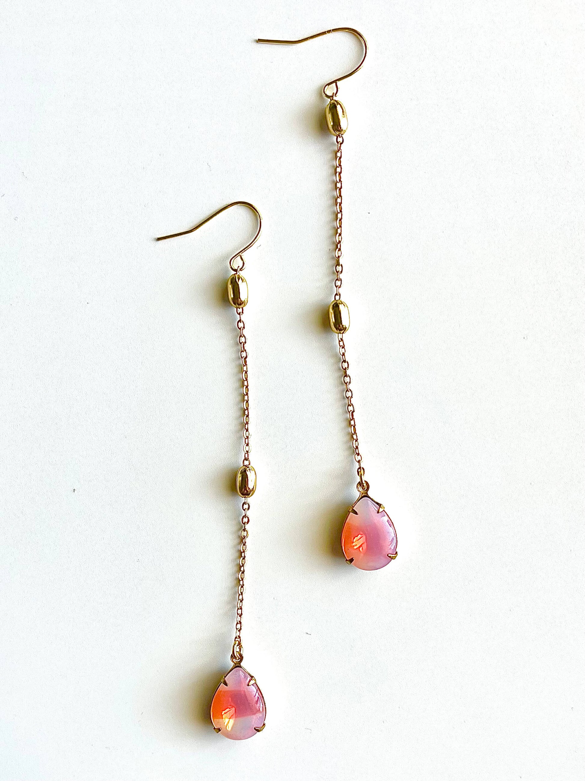 Pair of earrings with pink teardrop-shaped beads on a white background