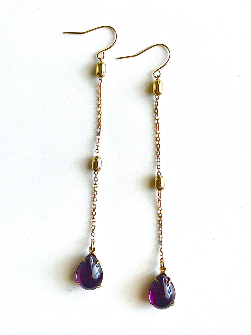 Gold chain earrings with purple teardrop beads on a white background