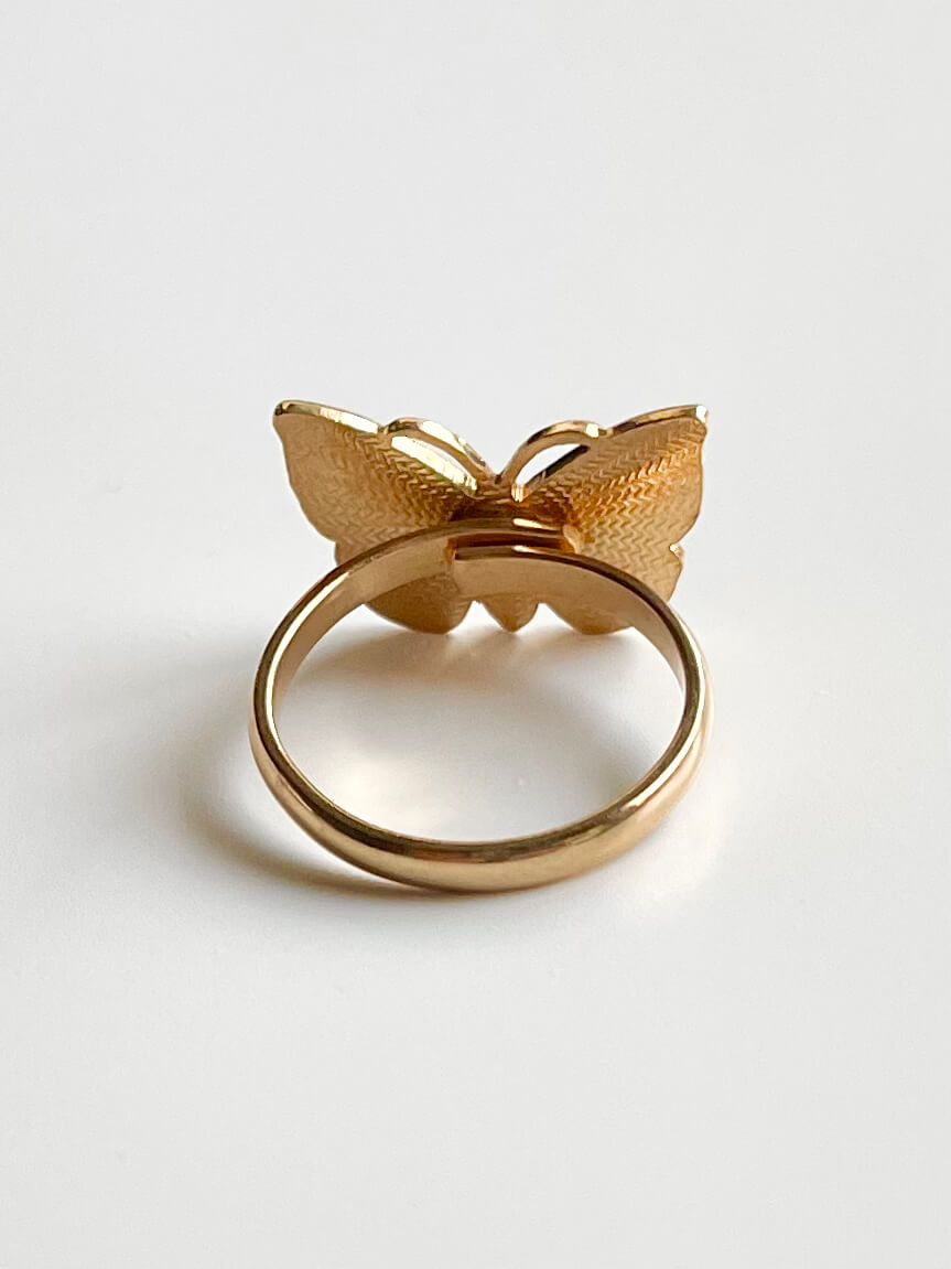 Yellow brass butterfly shaped ring with adjustable band, shown from the back of the ring