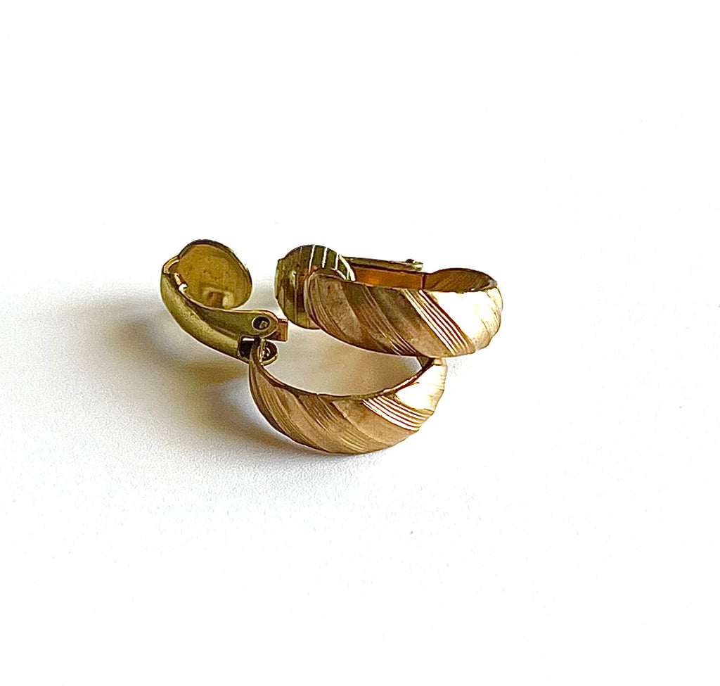 Yellow brass clip on small hoop earrings on a maroon background