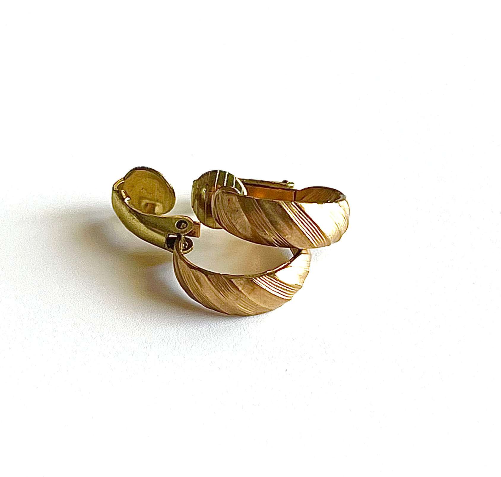 Yellow brass clip on small hoop earrings on a maroon background