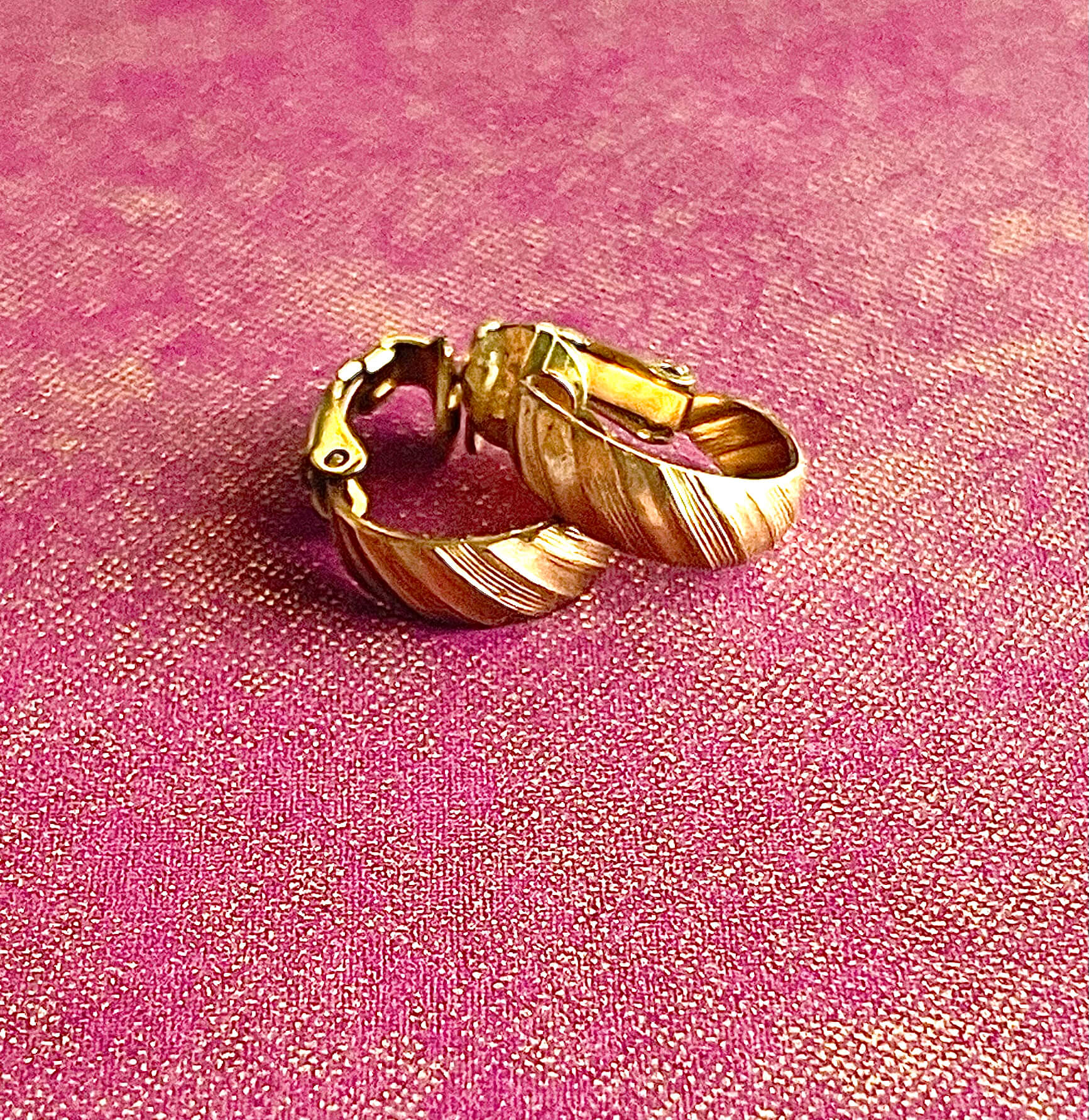 Yellow brass clip on small hoop earrings on a maroon background