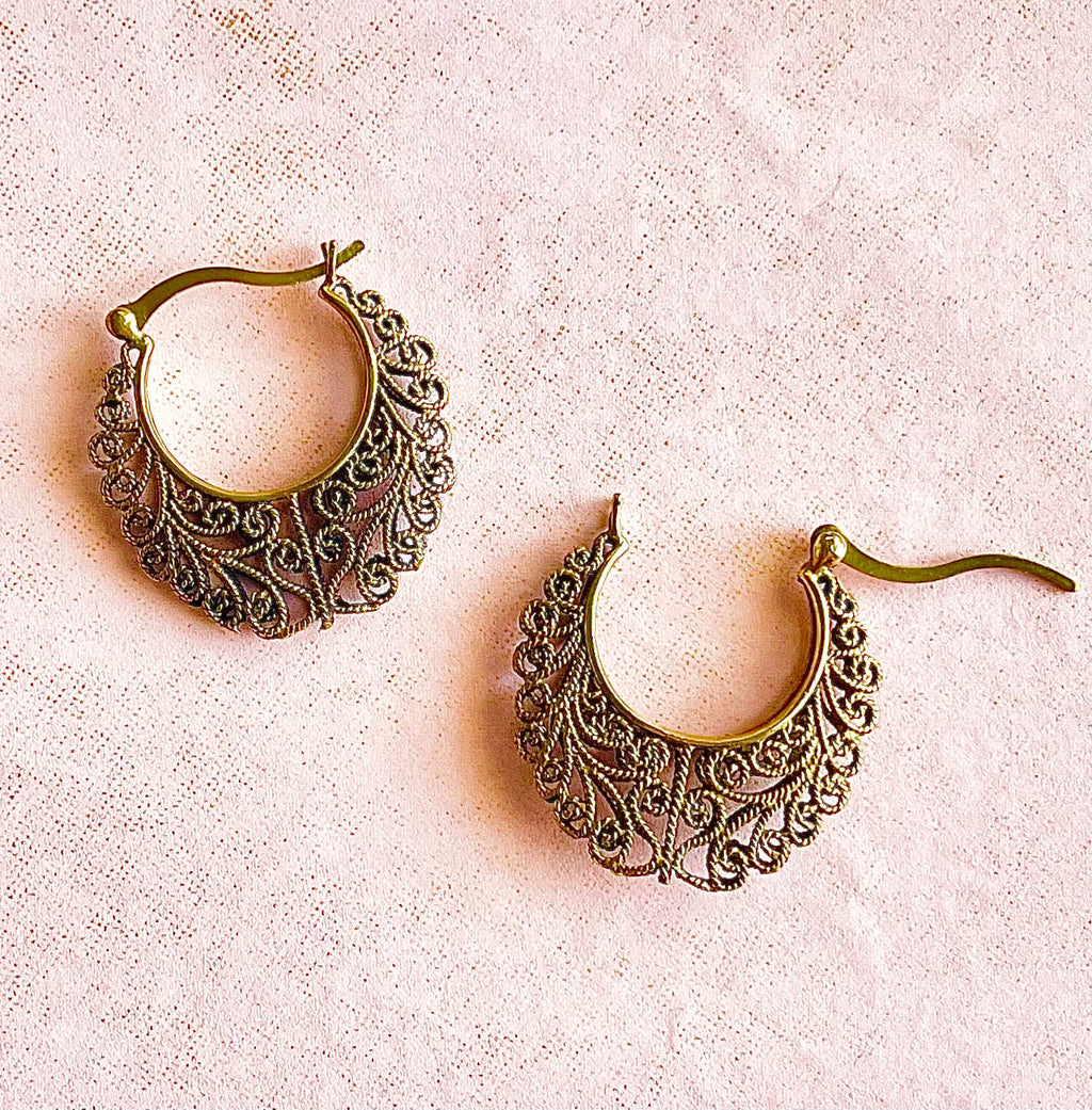 Bronze colored brass filigree earrings on pink background