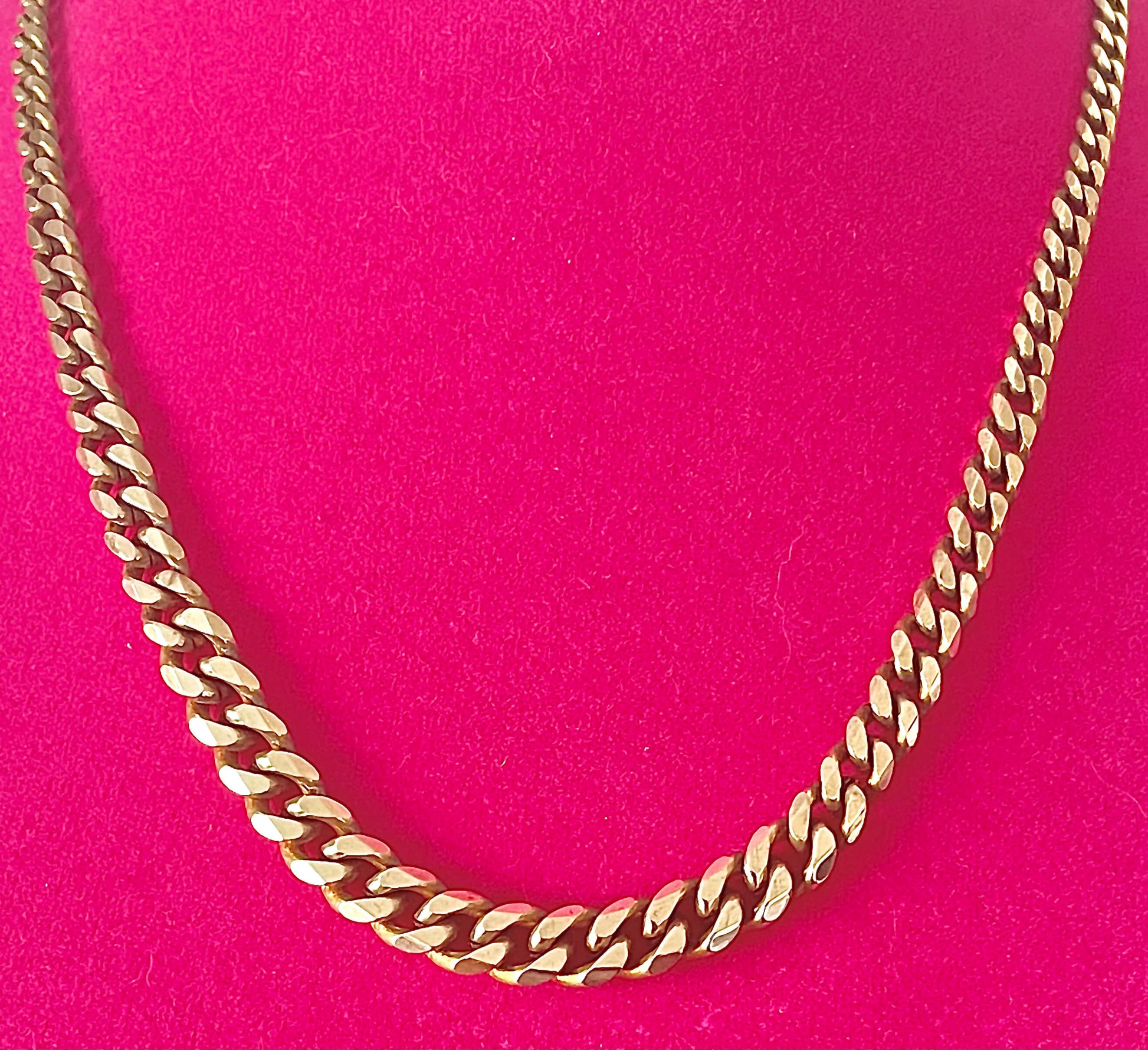Yellow brass graduated curb chain necklace on a hot pink background