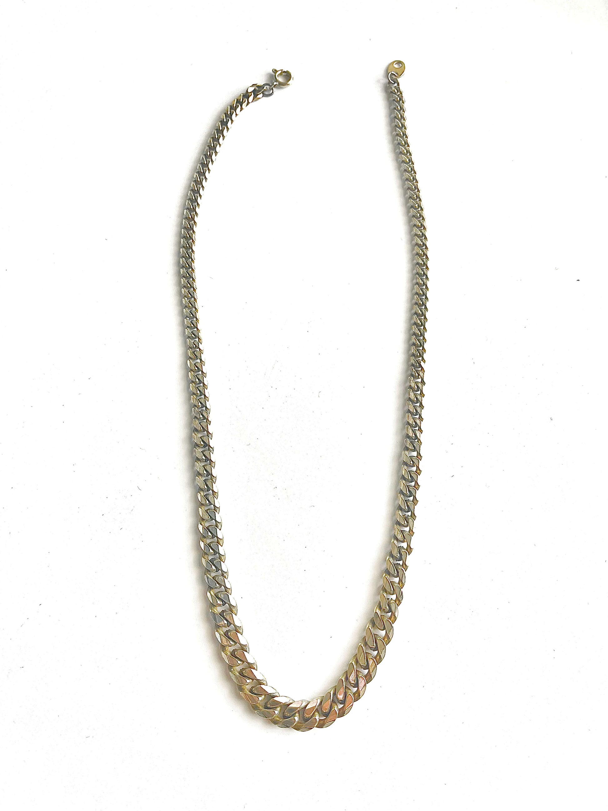 Yellow brass graduated curb chain necklace on a white background