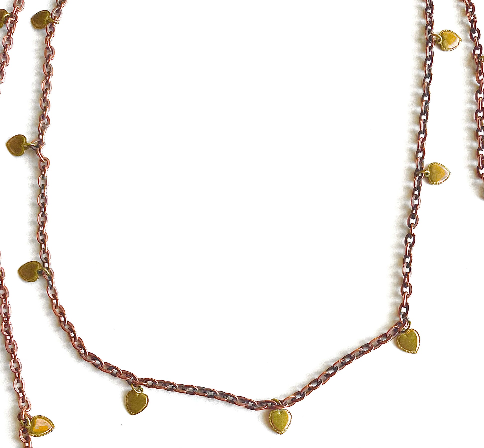 Copper brass necklace with yellow brass heart charms on a white backdrop