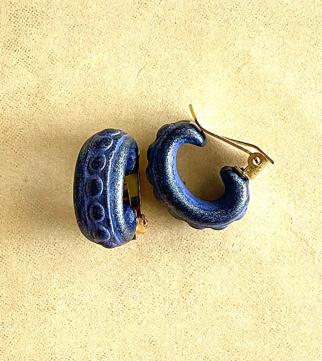 Yellow brass and purple acrylic clip-on earrings with dot details on white background