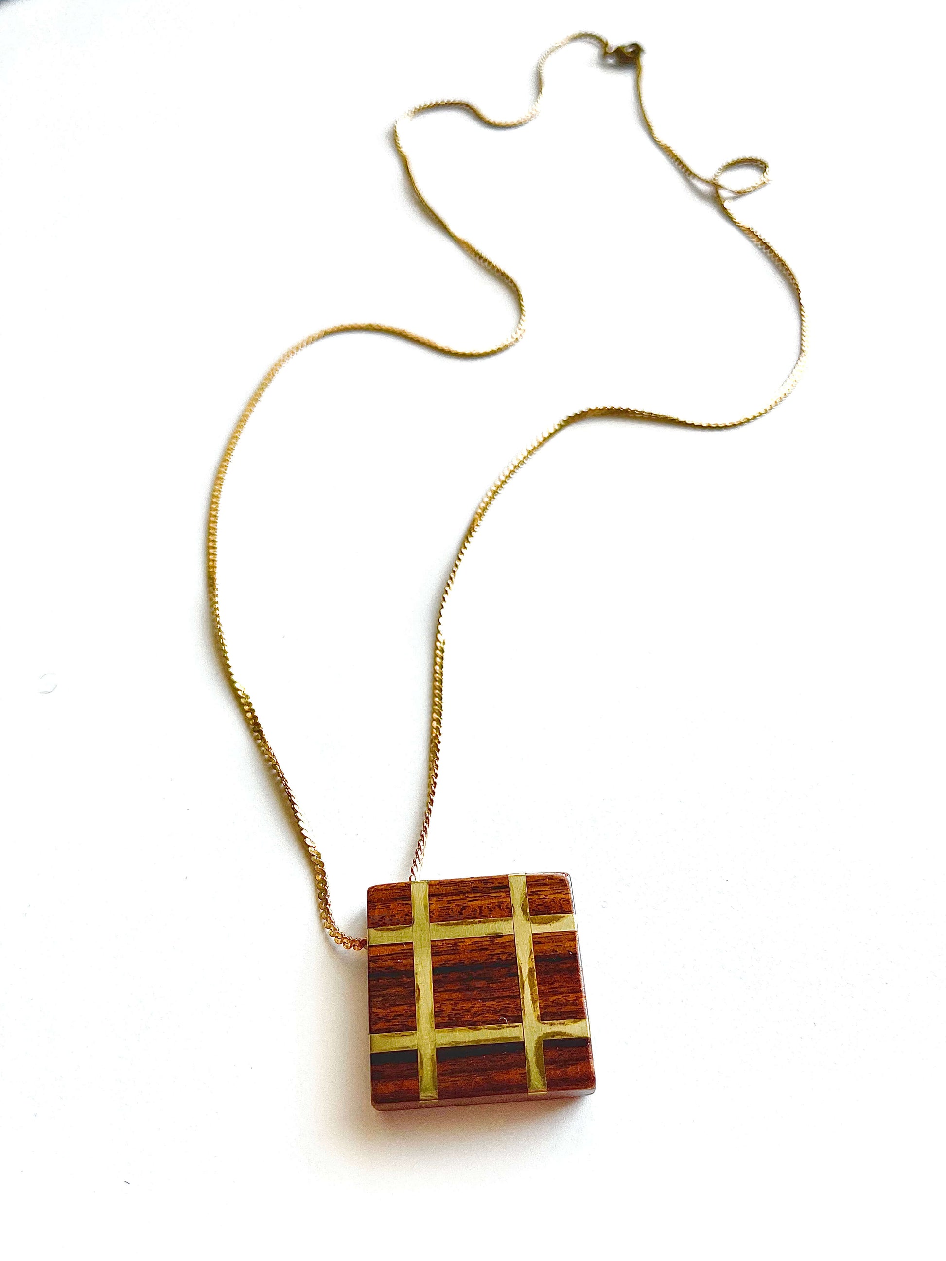Square wood pendant with yellow brass grid inlay on yellow brass chain with white background