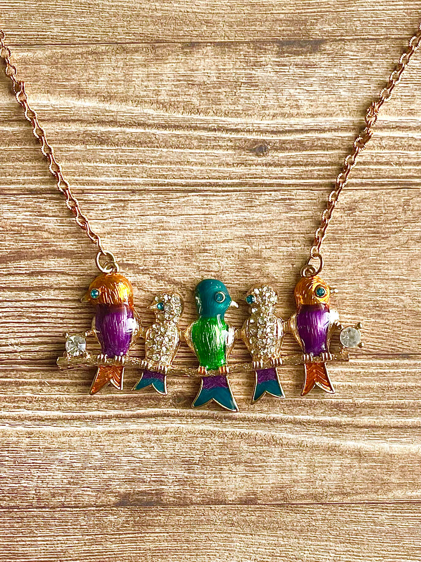 Necklace with colorful bird-shaped pendants on a wooden surface