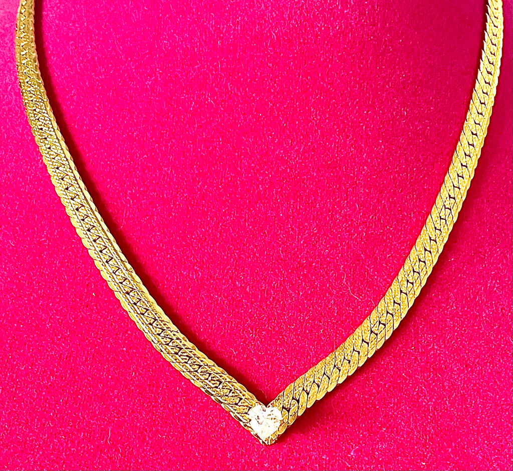 Yellow brass flat curb necklace with heart shaped crystal on pink background